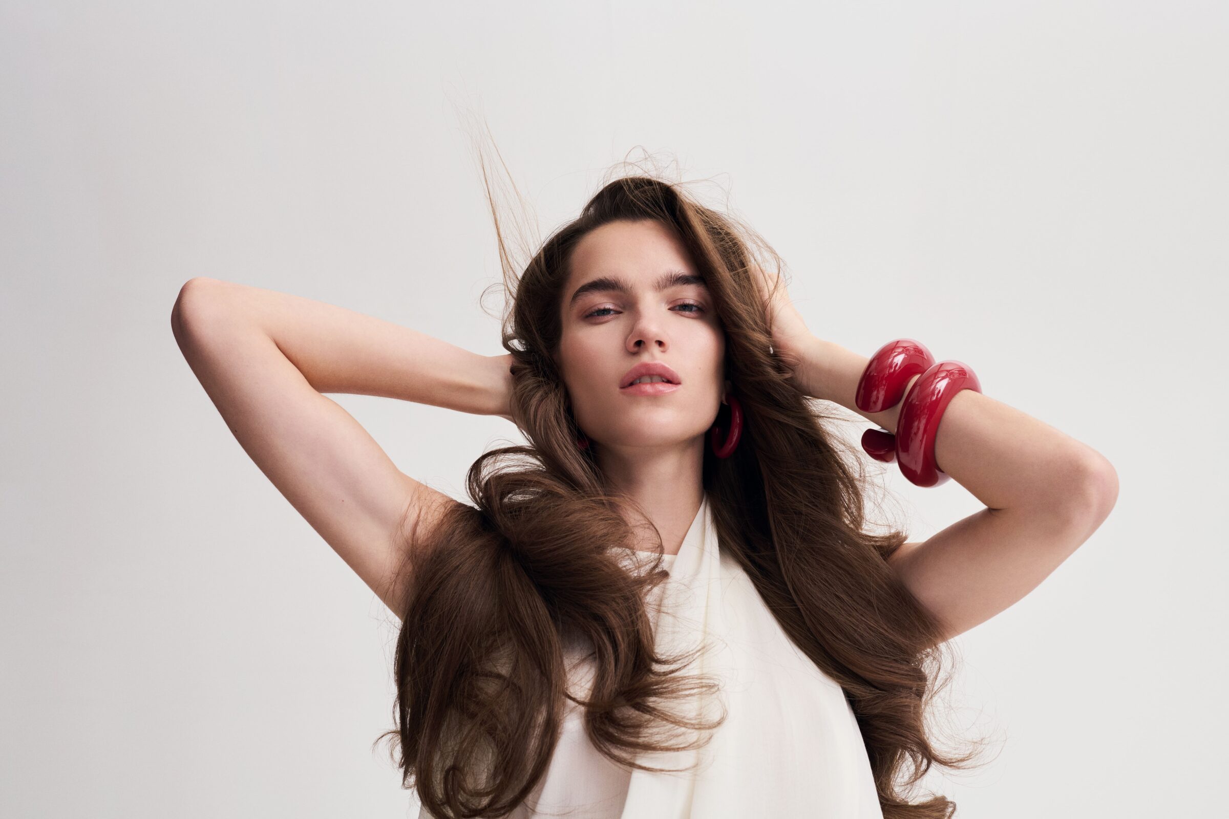 Modella con capelli castani lunghi e bracciali rossi