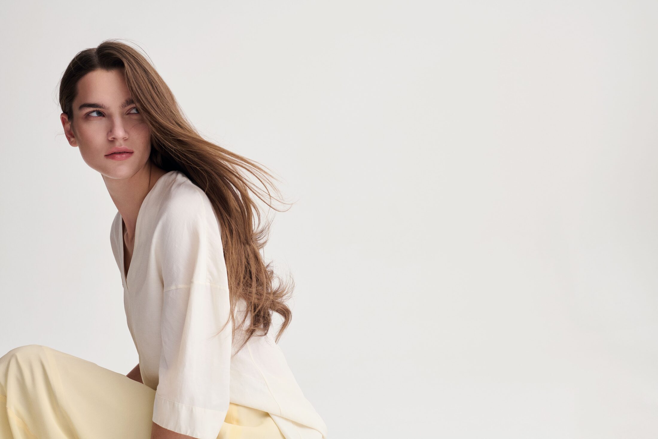 Modella seduta con capelli lunghi e camicia bianca