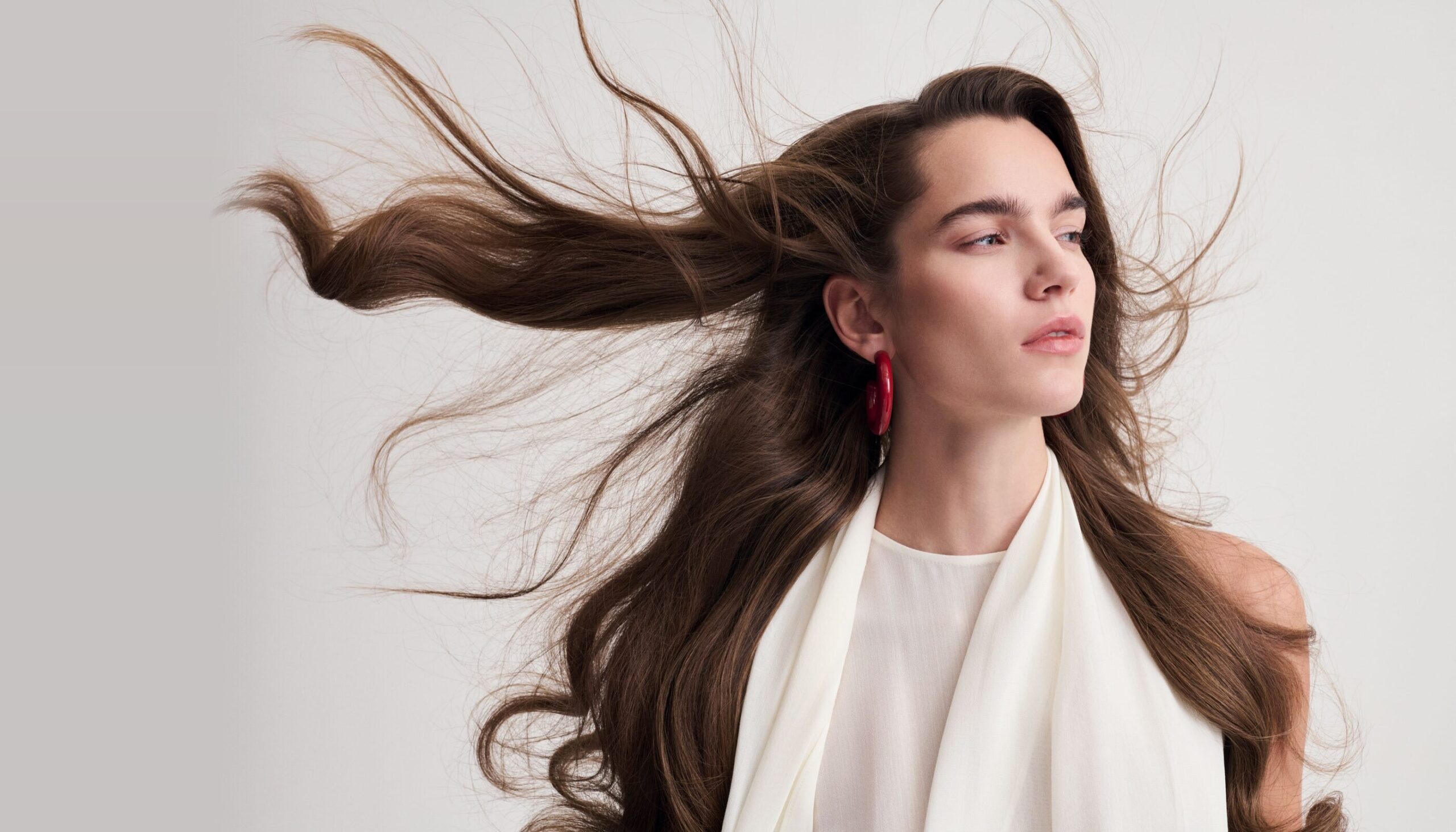 Modella con lunghi capelli castani mossi dal vento